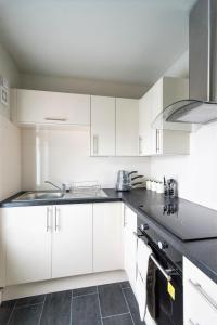 スウィンドンにあるSwindon City Centre Duplex - EnterCloud9SAの白いキャビネットとシンク付きのキッチン