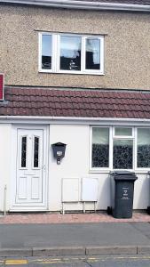 a white building with two windows and a trash can at Swindon City Centre Duplex - EnterCloud9SA in Swindon