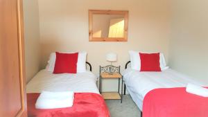 a bedroom with two beds with red pillows and a mirror at Swindon City Centre Duplex - EnterCloud9SA in Swindon