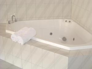 a white bath tub in a white tiled bathroom at Eltham Motor Inn in Eltham
