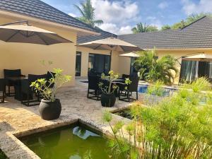 a patio with a pond with chairs and umbrellas at Grand Amber Villa in Diani Beach