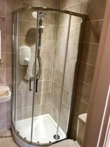 a shower with a glass door in a bathroom at Bromwell Court in Llandudno