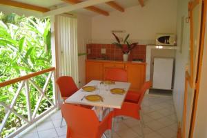 uma cozinha com uma mesa branca e cadeiras vermelhas em Fleurs des Iles em Deshaies