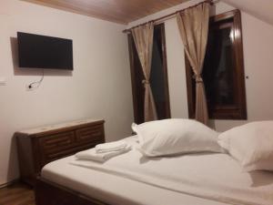 a bedroom with a bed with white pillows and a television at Denisa's Lodge in Arieşeni
