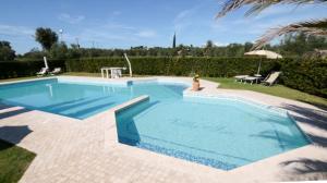 a swimming pool in a yard next to a hedge at Agriturismo Villa Isa in Follonica