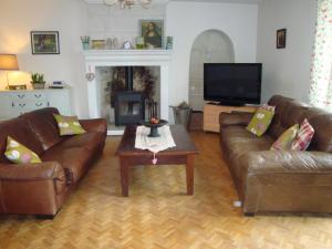 a living room with two leather couches and a tv at 'La Maison Catalpa' French Farmhouse with Pool & Jaccuzi in Saint-Privat-des-Prés