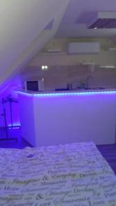 エゲルにあるMiNa apartmanのベッド1台付きの部屋、紫色の照明が備わるバー