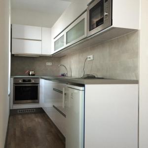 una cocina con armarios blancos y electrodomésticos de acero inoxidable en Elf en Kolín