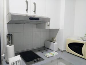 a kitchen with a microwave and a stove top oven at Alfaqueque Apartment in Seville