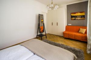 プラハにあるNational Theater Ruterra Flatのベッドルーム1室(ベッド1台、オレンジ色のソファ付)