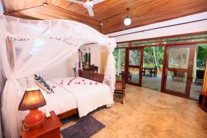 a bedroom with a bed with red flowers on it at Selnara Private Luxury Villa and Ayurveda Spa in Bentota