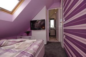 a purple room with two beds and a tv at Mátyás Apartmanház in Gyula