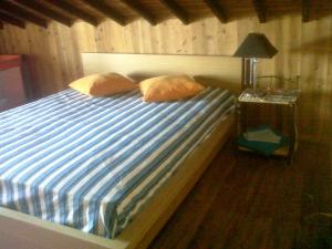 1 cama con sábanas de rayas azules y blancas y mesita de noche en Join our relaxed house near the beach - Mosteiros en Mosteiros