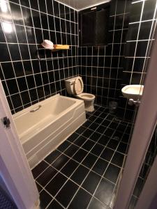 礁溪鄉的住宿－亞仕登旅館，黑色瓷砖浴室设有浴缸和卫生间