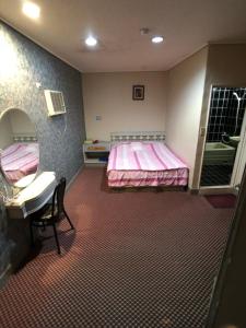 a room with two beds and a desk and a mirror at Ya Shi Deng Hotel in Jiaoxi