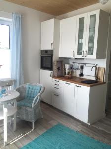 a kitchen with white cabinets and a table and a chair at Meeresbrise in Laboe