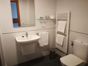 een badkamer met een wastafel, een toilet en een spiegel bij Pension Restaurante La Bombilla in A Estrada