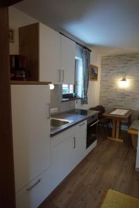 uma cozinha com armários brancos, um lavatório e uma mesa em Haus Rosenegg em Brixen im Thale