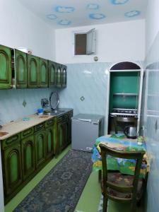 uma cozinha com armários verdes, uma mesa e uma cadeira em Keka Nubian House em Aswan