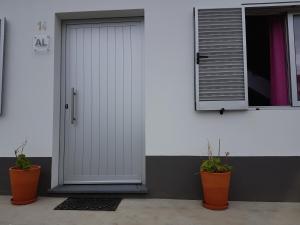 a white door with two plants next to a window at Our relaxing holiday home in Mosteiros