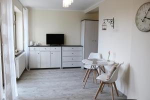 a white room with a table and chairs and a clock at Gościrada in Darłowo