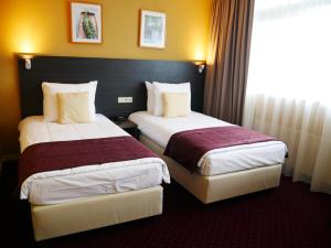 a hotel room with two beds and a window at Hotel het Oosten in Alphen aan den Rijn