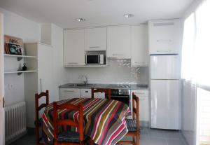 BarañáinにあるÁtico en Pamplonaの白いキャビネット、テーブルと椅子付きのキッチンが備わります。
