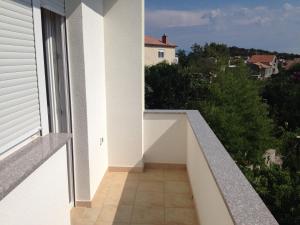 uma varanda vazia de uma casa branca com uma janela em Apartmani Dorita em Mali Lošinj