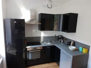 a kitchen with a black refrigerator and a sink at Ptit Savoy in Saint-Nectaire