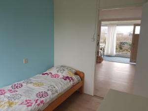 a bedroom with a bed and a door leading to a patio at Heerlijk aan Zee in Julianadorp