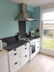 a kitchen with white cabinets and a stove top oven at Heerlijk aan Zee in Julianadorp
