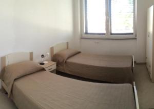 - 2 lits dans une petite chambre avec fenêtre dans l'établissement Dimora salentina, à Uggiano la Chiesa