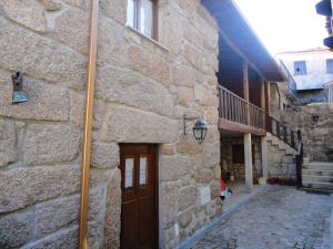 - un bâtiment en pierre avec une porte en bois et un escalier dans l'établissement Refúgio da Geira, à Campo do Gerês