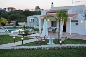 a house with a patio and a table with a umbrella at The Well in Chorafakia