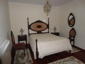 a bedroom with a bed and two chairs and a mirror at Melodia do Campo in Terras de Bouro