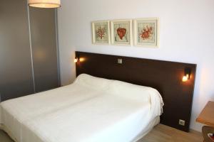 a bedroom with a white bed and two pictures on the wall at L'Attrachju in Corte