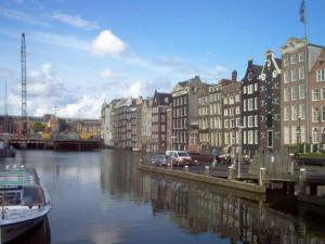 a river with buildings and a boat in a city at Fletcher Hotel Amsterdam in Amsterdam