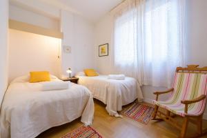 a bedroom with two beds and a chair and a window at Central Almuñecar, Beach Playa 125 metres, by Old Town in Almuñécar