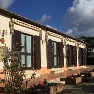a building with black shuttered windows and flowers at Poggio Moretto in Manciano
