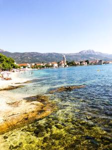 a view of a beach with people swimming in the water at Short Street Apartments in Kaštela