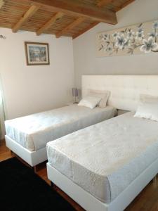 AmorosaにあるCasa do campo do fornoの白い壁と木製の天井が特徴の客室で、ベッド2台が備わります。
