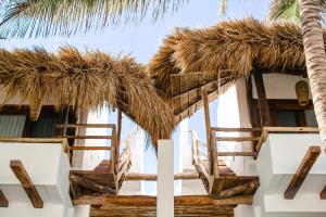 a resort with chairs and palm trees at The Beach Tulum Hotel in Tulum