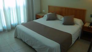 a bedroom with a large white bed with a wooden headboard at Hotel Albatros in Gandía