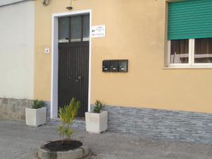 a building with a black door and two potted plants at PORRINO Guest House - Affittacamere in Alghero