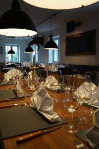 una larga mesa de madera con gafas y servilletas. en Mara Restaurant & Hotel en Dießen am Ammersee