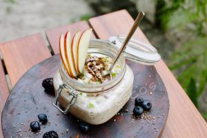a jar of yogurt with apples and blueberries on a table at The Beach Tulum Hotel in Tulum