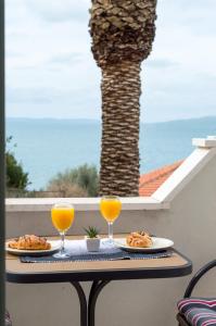 een tafel met twee glazen sinaasappelsap en eten bij Boutique Wind Rose Apartment by the beach in Podstrana