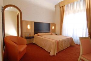 a bedroom with a bed and a chair and a mirror at Villa Luisa in Todi