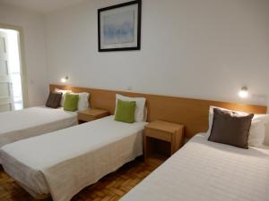 a hotel room with two beds with green pillows at Guesthouse Coimbra City in Coimbra