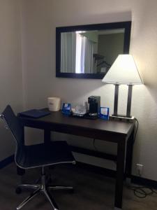 a desk with a lamp and a chair in a room at Baymont by Wyndham Phoenix I-10 near 51st Ave in Phoenix